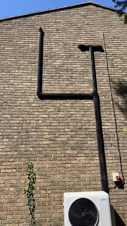 Black air conditioning pipe run set out squarely down a brick wall to the outdoor unit