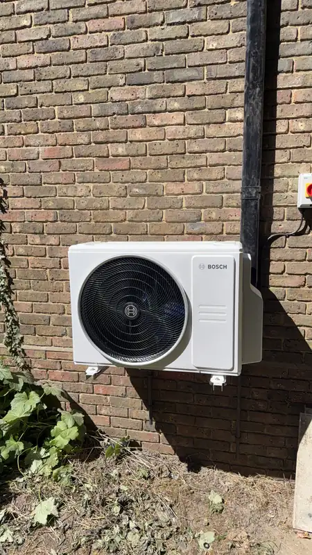 Bosch outdoor air conditioning unit mounted on brackets against brickwork