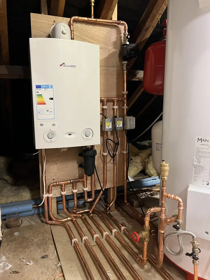 New boiler and hot water cylinder installed in a loft with tidy pipework