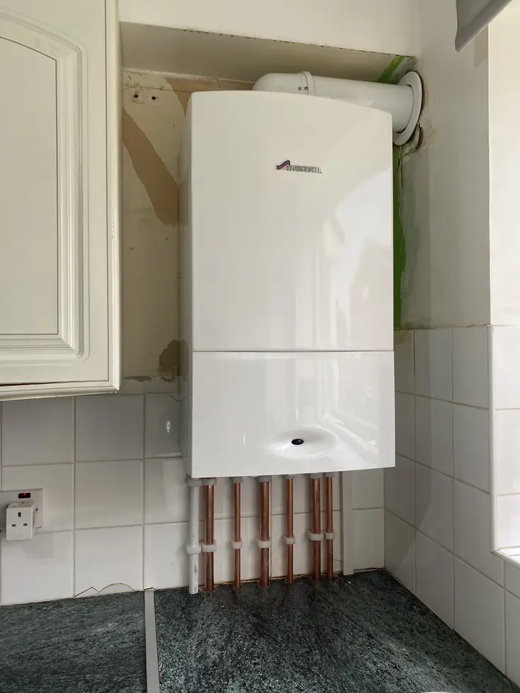 New Worcester combi boiler in a kitchen cupboard with copper pipework below
