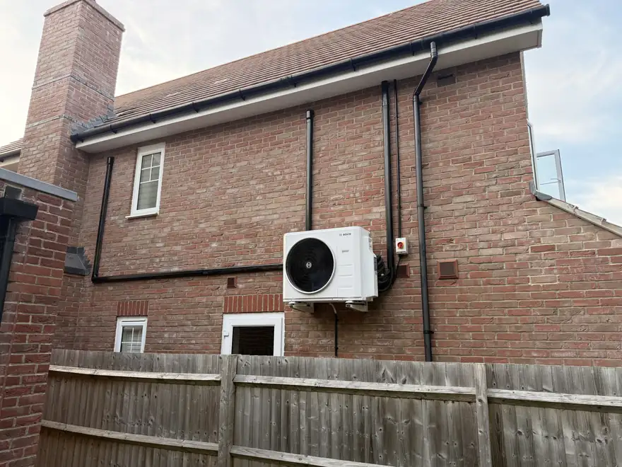 Outdoor air conditioning unit and pipe run on the rear wall of a house